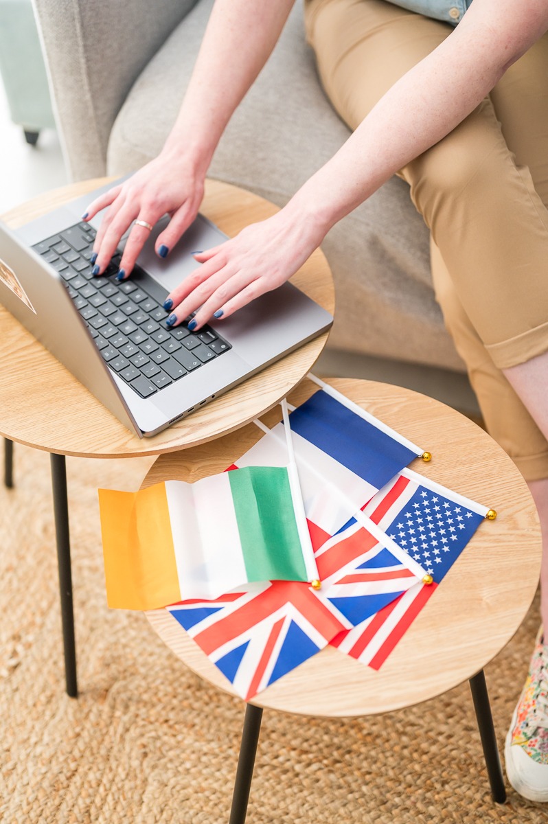 A translator working on a laptop, UK flag, Irish flag, French flag, US flag.